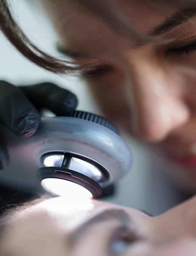 Dermatolog examining patient's skin